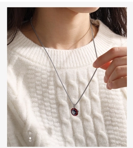 Primer plano de un colgante de brújula náutica en acero titanio con esmalte rojo y azul