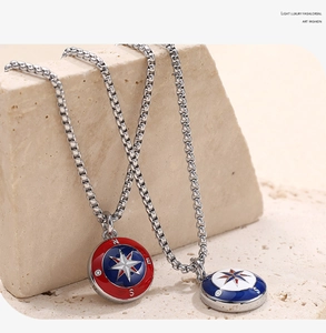 Detalle de collares de brújula esmaltados en rojo y azul sobre piedra natural rugosa
