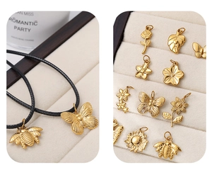 Detailed close-up of 18K gold butterfly and leaf pendants on a white jewelry display