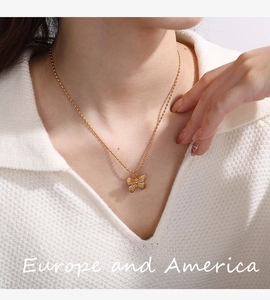 Detail view of a 18K gold plated butterfly pendant on a beaded chain worn by a model