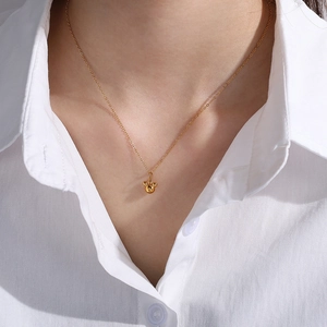 Polished golden necklace with three-ball pendant design on model wearing a white shirt