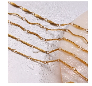 Macro view of 18K gold plated textured wavy link chain with artistic water droplet background