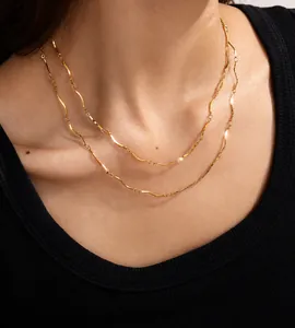 Close-up of minimalist layered 18K gold-plated chain necklaces worn by a model