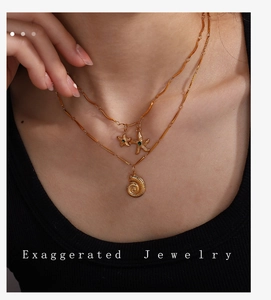 Close-up of double layer gold necklace with starfish charms and green gemstone