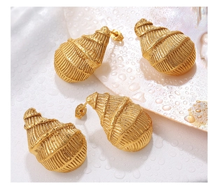 Detalle macro de pendientes de concha dorados con textura en espiral y gotas de agua