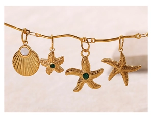 Vista macro de colgantes dorados de estrella de mar y concha con piedras verdes