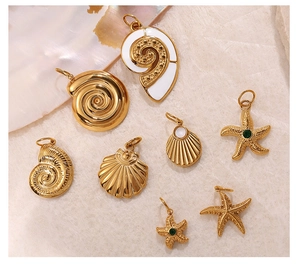 Detalle de colgantes de estrella de mar y concha en oro de 18K con piedras verdes