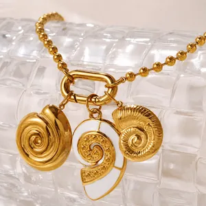 Detail von Muschel- und Schneckenanhängern an goldener Perlenkette auf Glasdekor