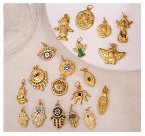 Macro shot of 18K gold plated Hamsa and Evil Eye pendants on a premium cream display