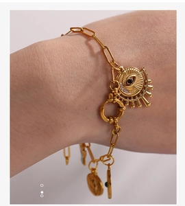 Detail of 18K gold-plated necklace with evil eye sunburst and green gem pendant