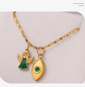 Macro detail of 18K gold plated stainless steel necklace with angel and green stone pendants