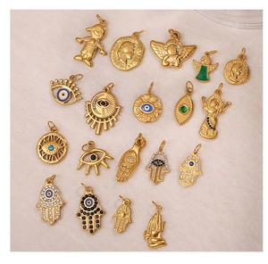 Collection of 18K gold plated stainless steel Hamsa hand and Evil Eye pendants on fabric