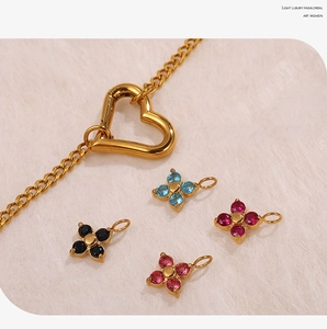 Close-up of gold chain with heart clasp and colorful four-leaf flower pendants on plush
