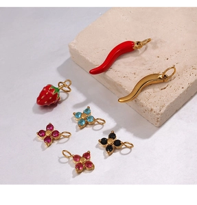 Macro shot of gold-plated chili and flower pendants with colorful enamel details