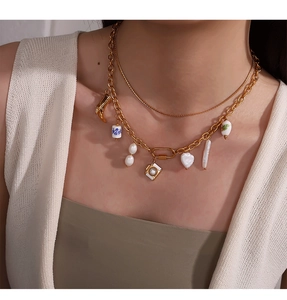 Detailansicht der zweilagigen Goldkette mit Keramik-Anhängern und Perlen an einem Model