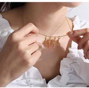Close-up of a gold chain necklace featuring Eiffel Tower and mermaid tail charms