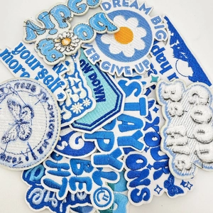 Close-up of blue and white embroidered patches with motivational quotes and daisy motifs