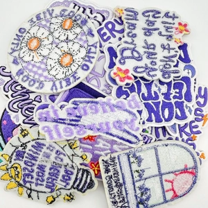 Detail of purple embroidery patches with floral patterns and motivational text labels