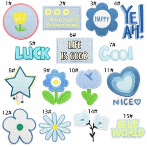 Macro detail of 15 blue flower embroidery patches with diverse patterns and slogans