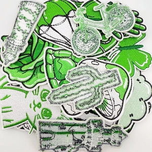 Detailed close-up showing green embroidered patches of cactus, bike, and mushroom shapes
