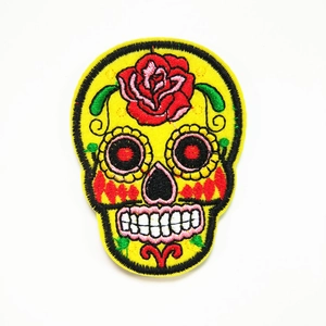 Detailopname van gele suikerschedel geborduurde patch met rode roos en kleurrijke stiksels