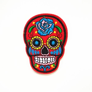 Macro-opname van rode Mexicaanse suikerschedel borduurpatch met blauwe roos en gele bloemen