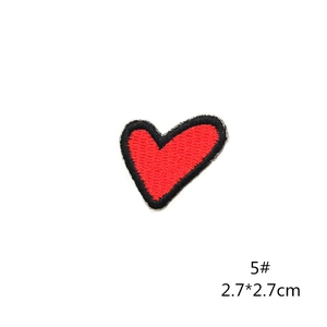 Detailed macro shot of a small red heart embroidered patch with black border trim