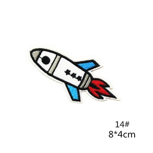 Detail of embroidered rocket patch featuring white body with blue wings and red fire