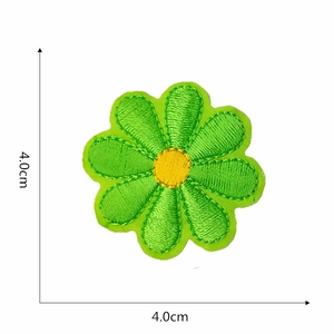 Detail view of a 4.0cm green embroidered flower patch with a yellow center and precise edges
