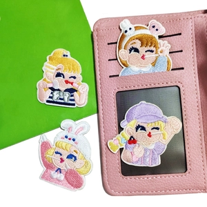 Detail of cute cartoon girl embroidered patches used on pink leather wallet slot