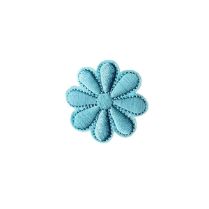 Detailed macro view of a light blue embroidered daisy patch with textured petals and neat edges
