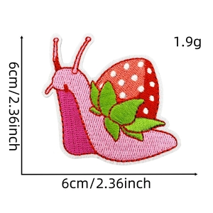 Close-up of strawberry snail embroidery patch with fine needlework and vibrant colors