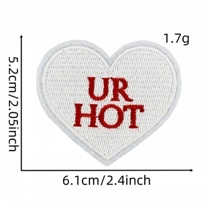 Détail d'écusson cœur rouge UR HOT montrant les dimensions 5.2x6.1cm et la texture de broderie