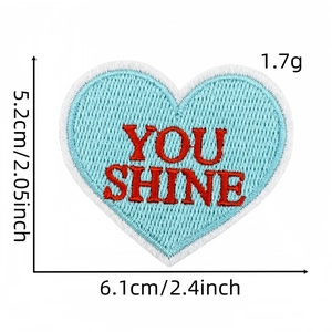 Détail macro du patch brodé en cœur 'YOU SHINE' avec dimensions et poids précis