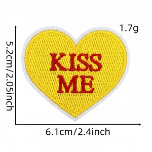 Détail d'écusson brodé en forme de cœur jaune avec texte KISS ME pour vêtements