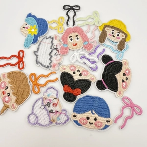 Detail of embroidered cartoon girl patches with smooth edges and colorful bow accessories