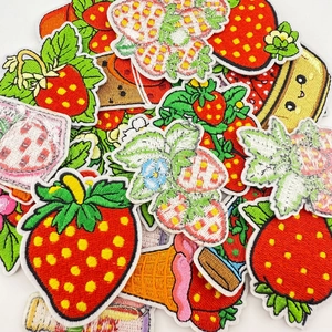 Detailed close-up showing vibrant strawberry and dessert embroidery patches with fine stitching