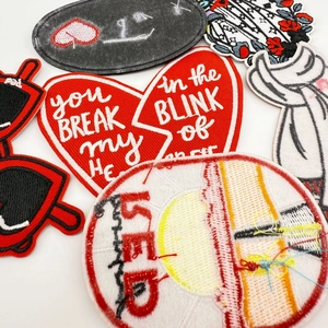 Detailed embroidery view showing various red heart patches and text on white background