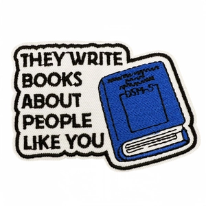 Cartoon book patch with 'They write books about people like you' embroidery