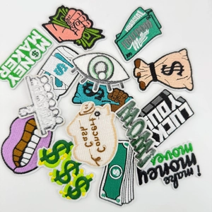 Detailed view of money themed embroidery patches showing texture and fine stitching
