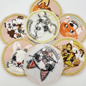 Close-up of assorted animal embroidery patches featuring cats and dogs with gold edges