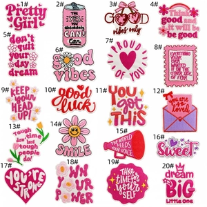 Detail view of 20 pink embroidered patches with motivational English slogans on white