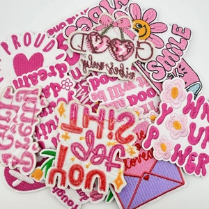 Detailed view of pink embroidered patches featuring daisies and motivational English words