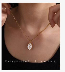 Collana con ciondolo ovale dorato con rilievo di luna e stelle su catena a corda indossata da modella