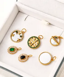 Dettaglio macro di ciondoli vintage dorati con zirconi e pietre preziose verdi