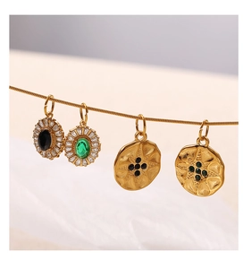 Dettaglio di quattro pendenti vintage in oro con pietre di zircone nero e smeraldo