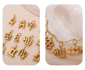 Dettaglio di ciondoli zodiacali placcati oro 18K su superficie in pietra naturale