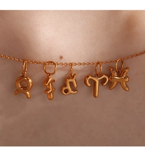 Dettaglio di ciondoli zodiacali in oro 18K con segni Toro e Leone su una catenina sottile