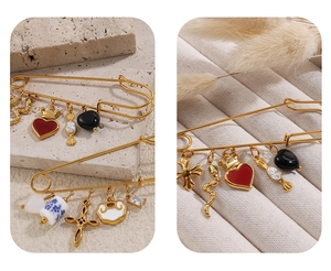Détail d'une broche épingle dorée avec pendentifs en émail et zircons sur fond texturé