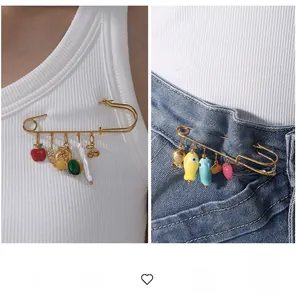 Broche épingle de sûreté avec breloques sur débardeur blanc et jean en denim bleu foncé